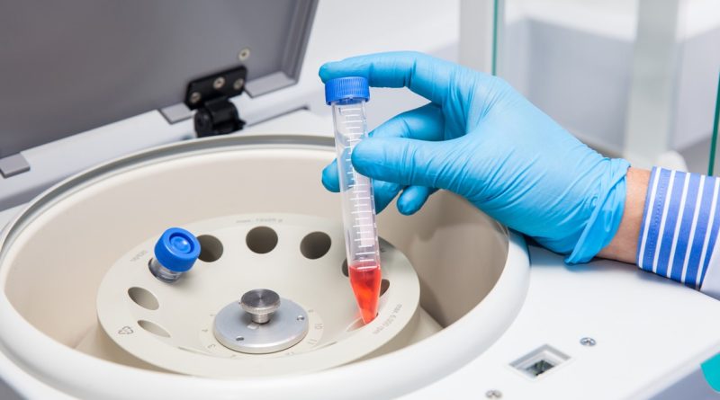 Cientista inserindo tudo em centrífuga de laboratório